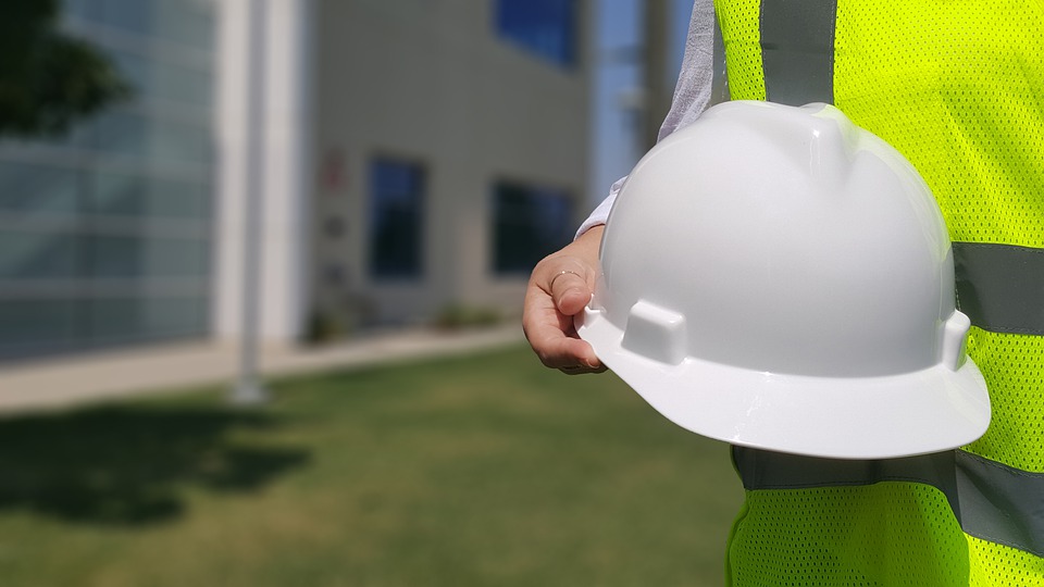 worker wearing high-visibility vest, holding hard hat